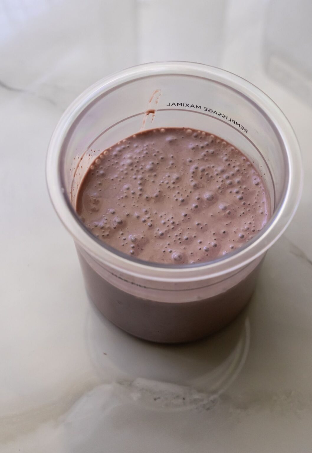 Acai ice cream in a clear pint container.