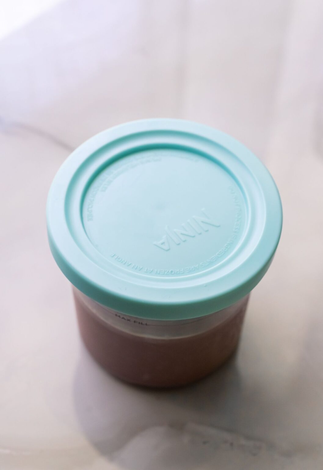 Acai ice cream in a clear pint container with lid.