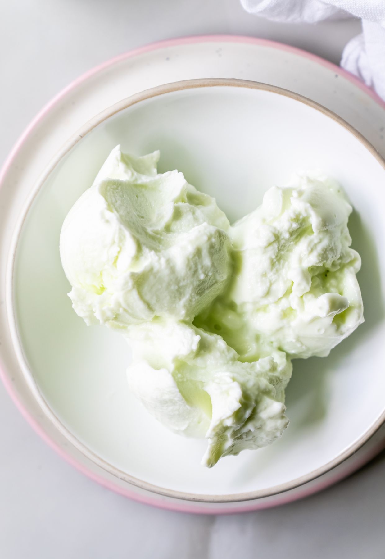 A white plate with three scoops of light green ice cream, a delightful example of gourmet desserts.