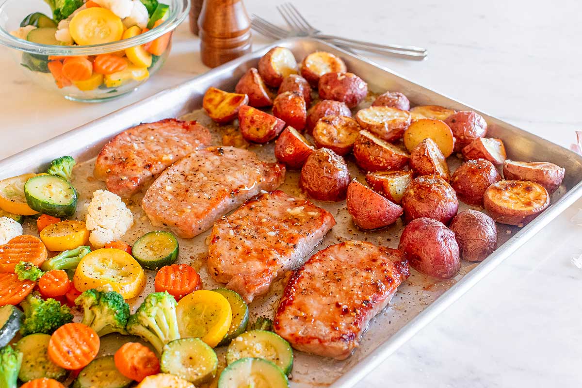 Pork chops, veggies and potatoes baked on a sheet pan. 
