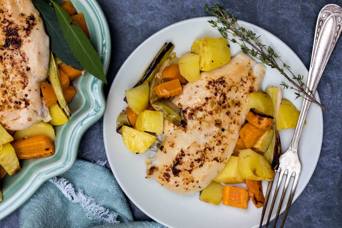 chicken breast with roasted vegetables on plate with fork