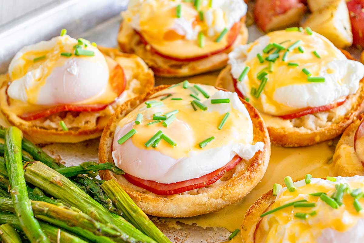 Eggs, hashbrowns, ham and hollandaise on a sheet pan with asparagus.