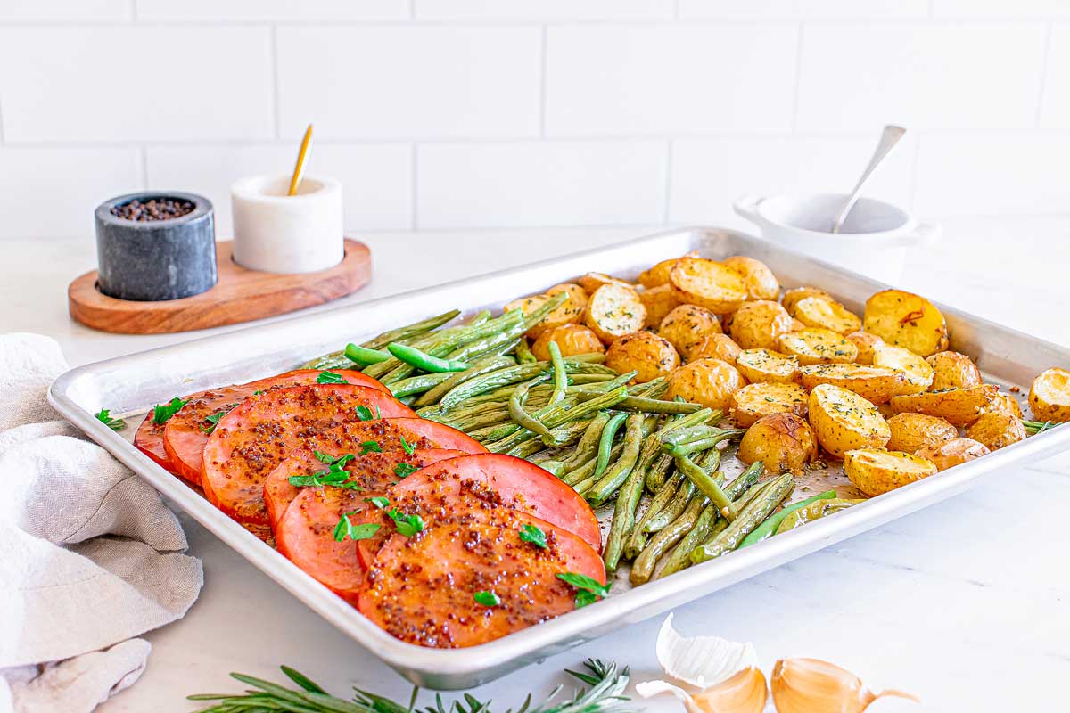 Ham steaks, green beans and potatoes cooked on a sheet pan.