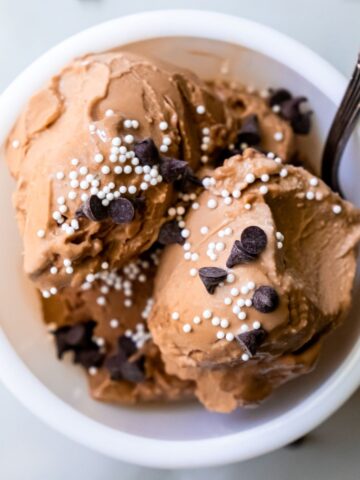 chocolate ice cream with sprinkles and chocolate chips with a spoon.
