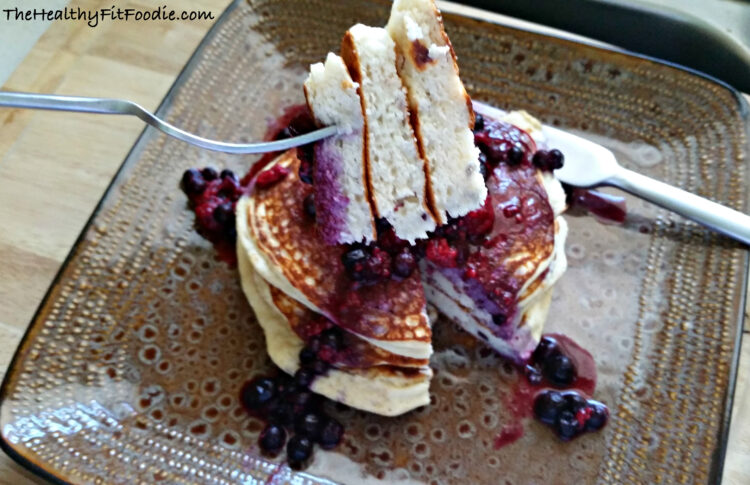 A slice of Gluten Free Protein Pancakes with Blueberry and Raspberry Toppings on a square platter.