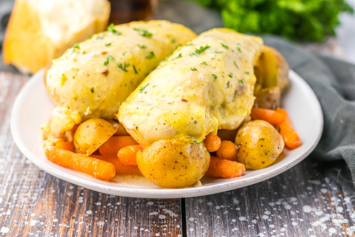 A plate of slow cooker ranch chicken with creamy sauce served with carrots and potatoes.
