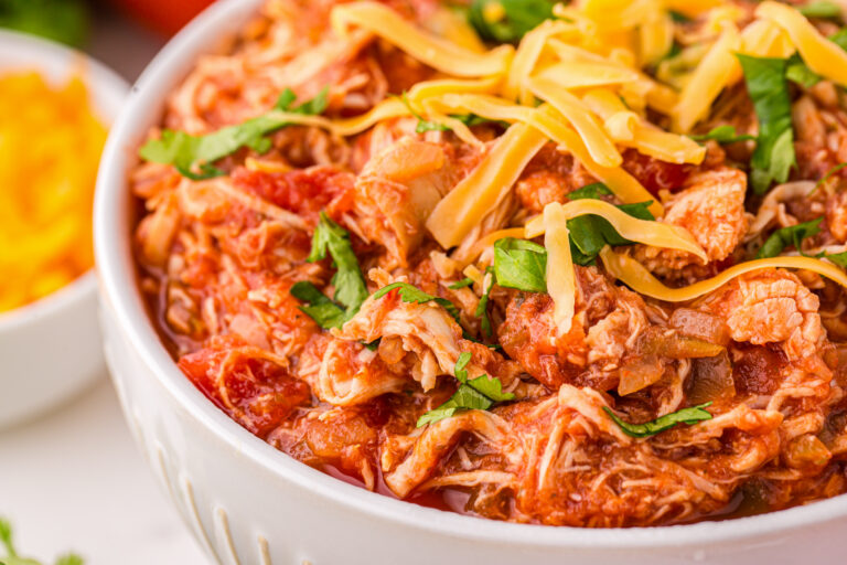 A photo of a bowl of salsa chicken in a white bowl, topped with shredded cheddar cheese