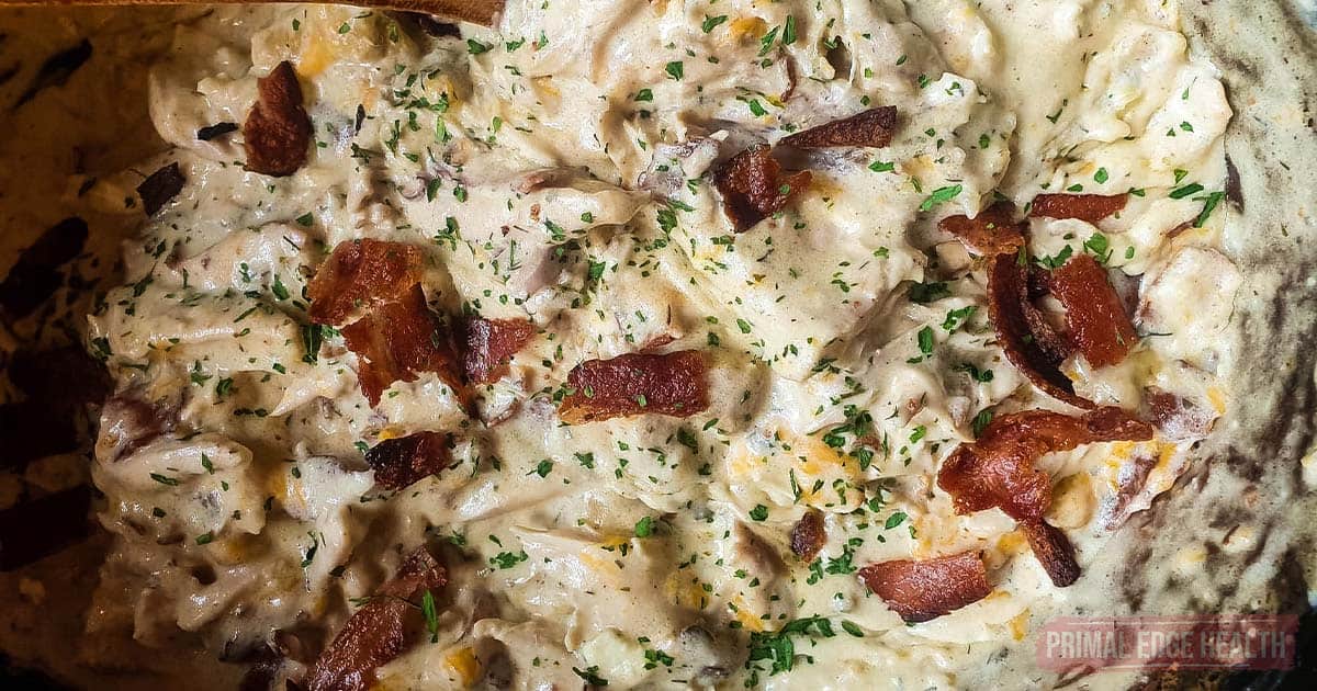 A picture of cheesy chicken with bacon and dried parsley.