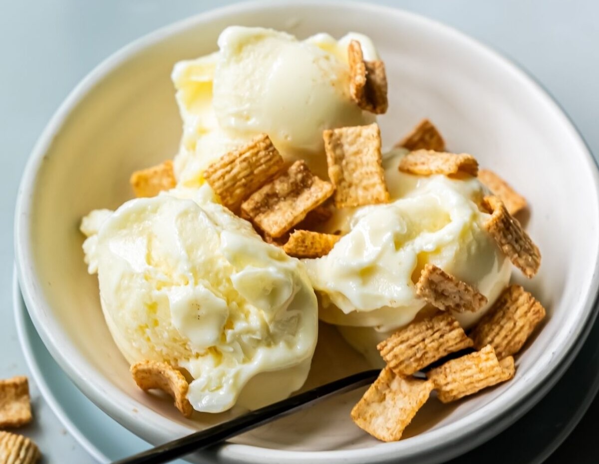 A bowl with three scoops of vanilla ice cream topped with pieces of cereal is one of the delightful options in our collection of 20 banana desserts.