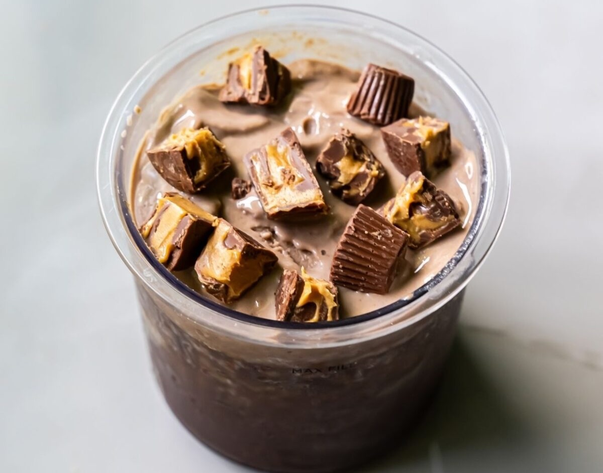 A cup filled with chocolate ice cream, enhanced by the magic of the Ninja Creami, topped with chunks of peanut butter cups.