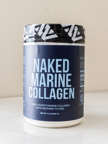 Container of Naked Marine Collagen with a black lid, featuring labels and text about wild-caught marine collagen.