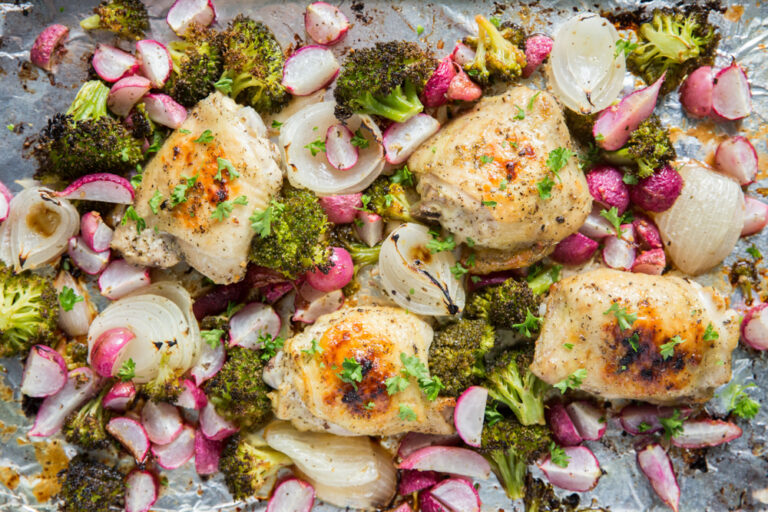 Sheet Pan Chicken and Vegetables on a sheet pan with foil, broccoli, onions, radishes, and parsley.