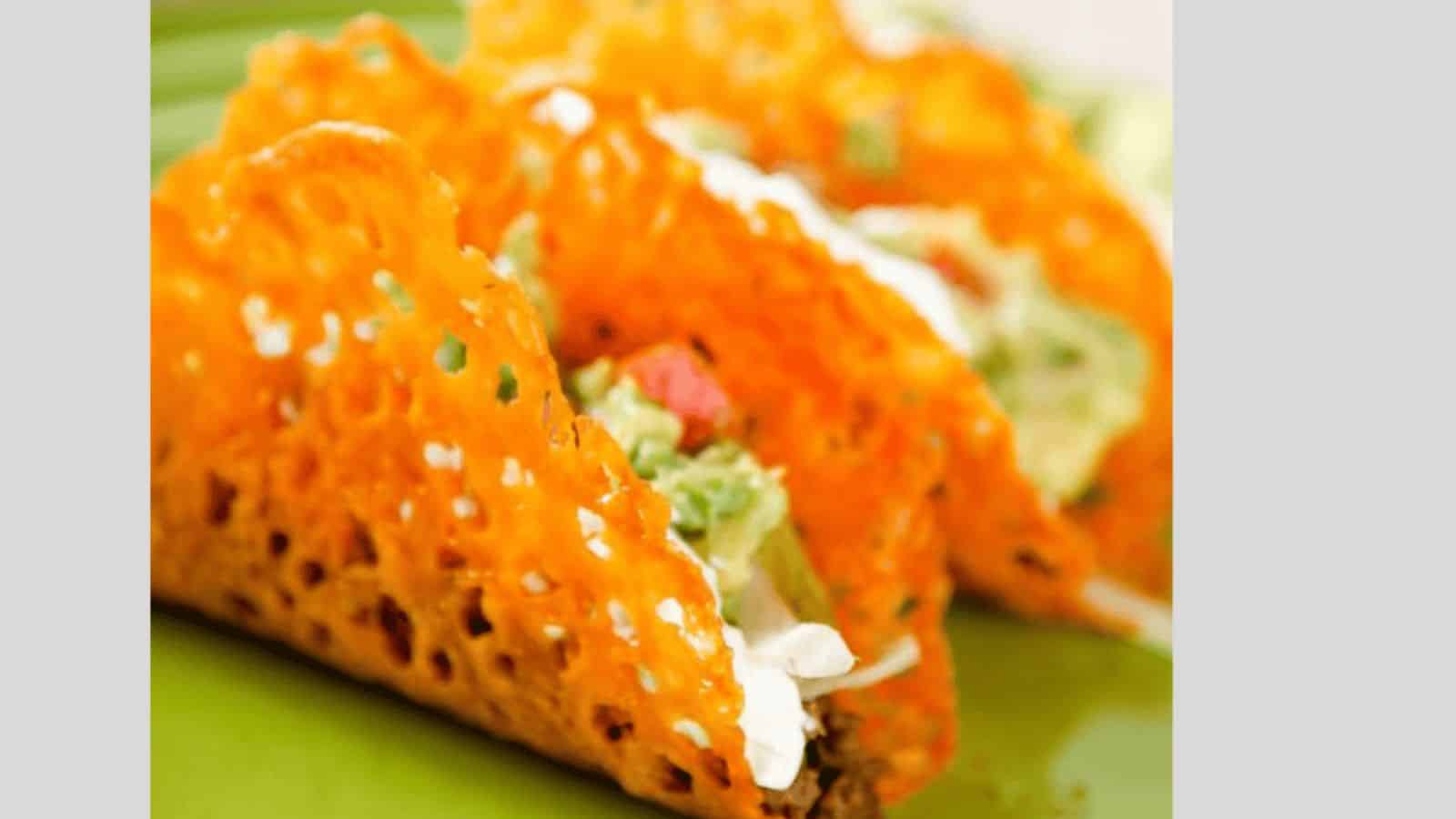 A cheese taco shell filled with ground beef, sour cream, guacamole, and tomatoes.