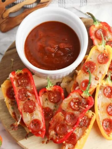 Pepperoni Pizza Peppers in a round chopping board with red sauce on the side
