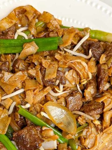 sliced beef, rice noodles, and vegetables in a plate