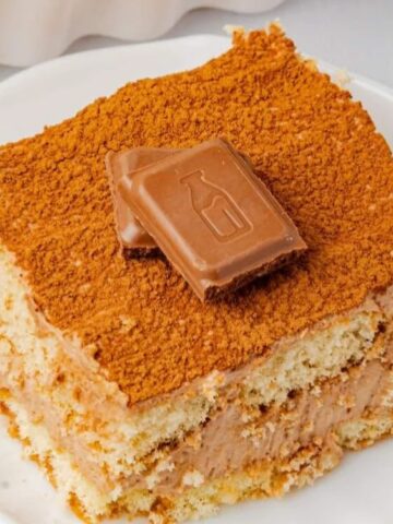 a slice of Chocolate Tiramisu in a saucer garnished with 2 pcs of chocolate on top