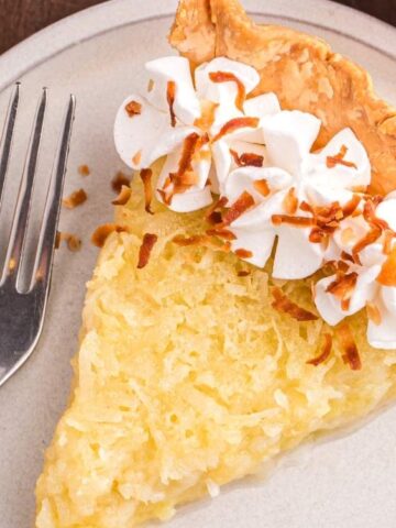 a slice of Coconut Custard Pie in a saucer with fork
