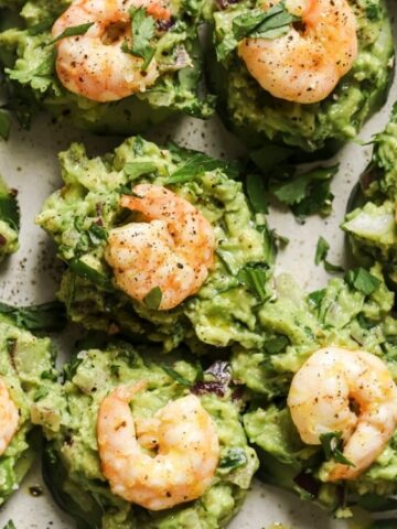 slice of cucumber top with guacamole and a piece of shrimp