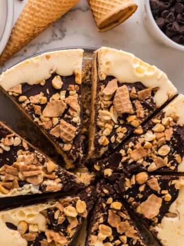 Drumstick Pie cut into pieces and a bowl of chocolate chips and nuts on the side with 2 ice cream cones.