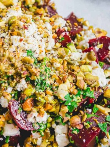 beets, crumbled feta and pistachios come together with fresh herbs and a lemon olive oil dressing top with feta cheese in a bowl
