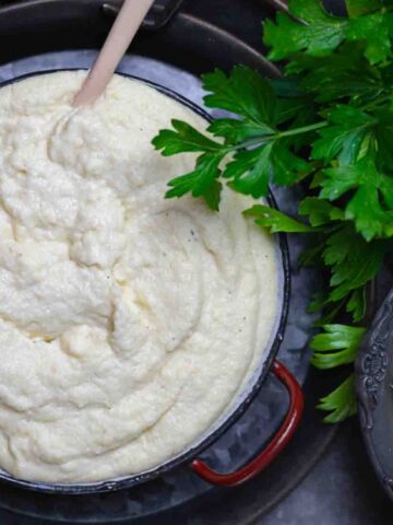 Mashed Cauliflower on a pot garnished with parsley.
