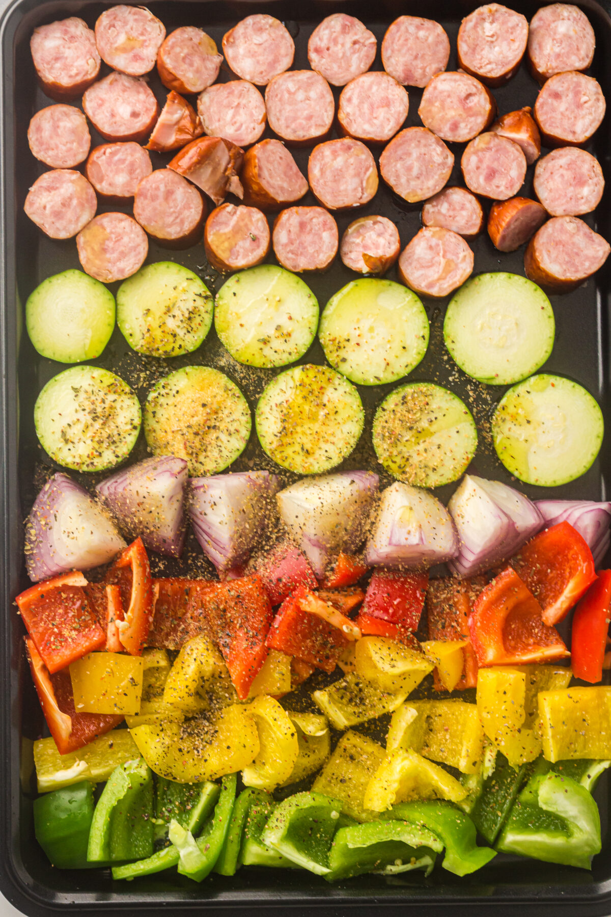 sliced sausage and veggies on a sheet pan.