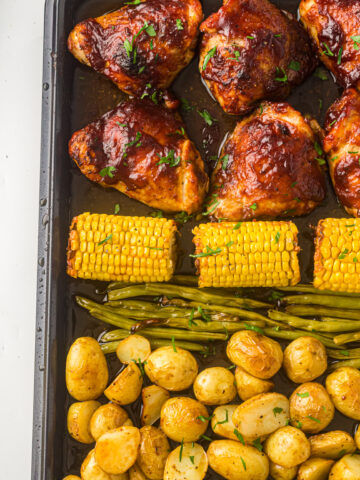 sheet pan with chicken thighs, corn, green beans and potatoes.