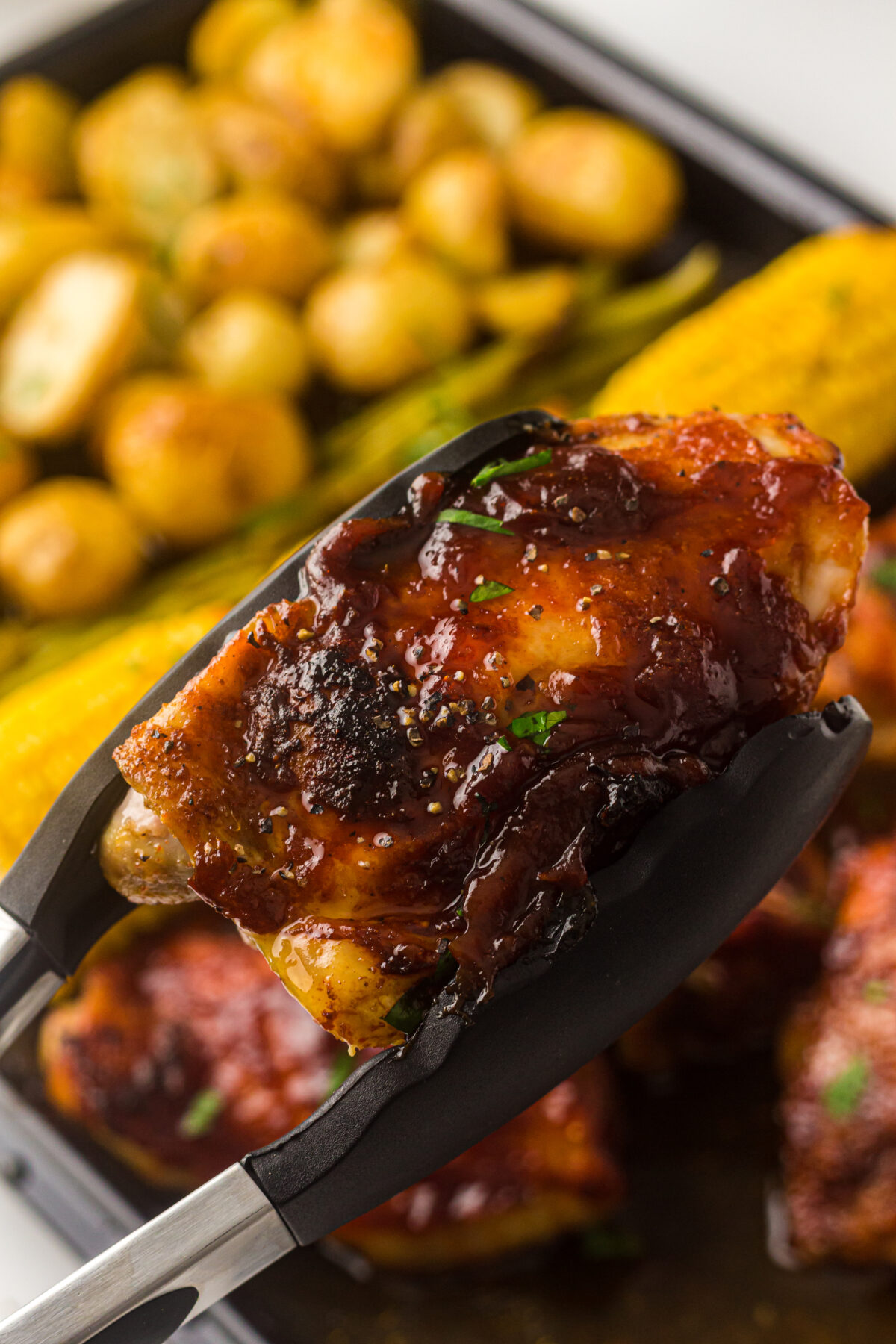 tongs holding a chicken thigh.