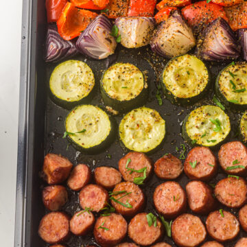 sliced veggies and sausage on a sheet pan.