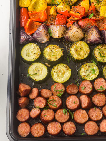 sliced veggies and sausage on a sheet pan.