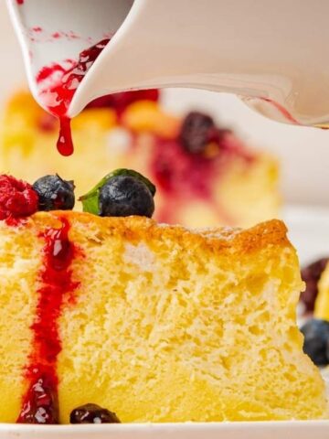 juggly japanese cheesecake slice top with blueberries and rasp berry poured with red strawberry jam