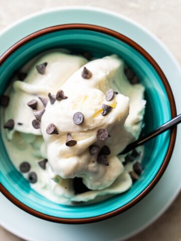 mint chocolate ice cream top with chocolate chips and a spoon in a bowl