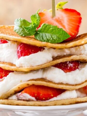 strawberries with pancakes and whipped cream an mint on top