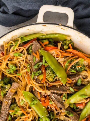 stir-fried noodle combines strips of beef, vegetables, and noodles, all tossed in a pot.