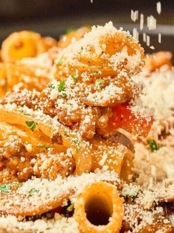 pasta with vegetables and mushroom sprinkled with parmesan cheese in a bowl.