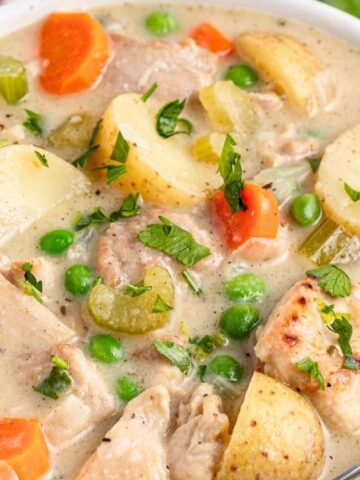 Chicken thighs pair up with vegetables and herbs, along with a creamy, meaty and sauce in a bowl