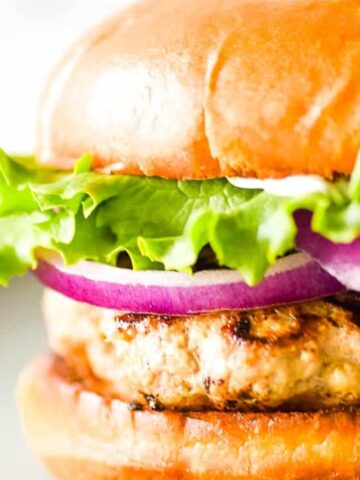 burger buns with turkey patty, lettuce, slice onion on a plate
