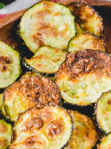 crispy air fried zucchini chips on a plate seasoned with garlic powder.