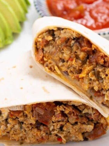 pita bread stuffed with cheese, sausage, onion and others . sliced avocado on the side and red dip sauce