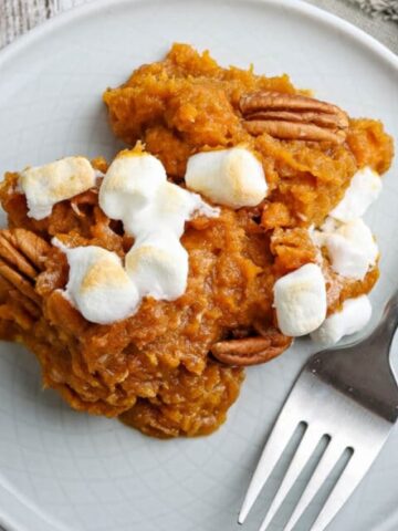 mashed sweet potato with marshmallows and a pecan in a plate.