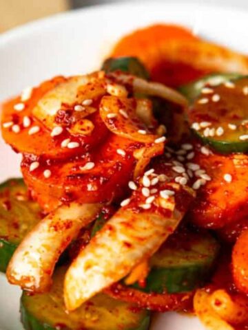 sliced cucumber, carrots and onion with korean kimchi marinate, sprinkled with sesame seeds