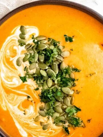 yellow orange soup , drizzled with coconut cream and toasted pumpkin seeds sprinkled over the top