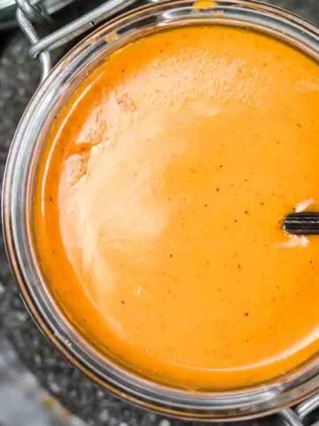 creamy orange brown sauce in a glass container with a spoon