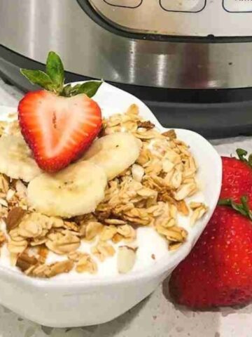 white Greek yogurt topped with oats, sliced banana and half slice strawberry on the bowl