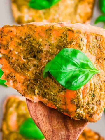 salmon in wooden spoon with pesto sauce on top and garnish with basil pesto leaf