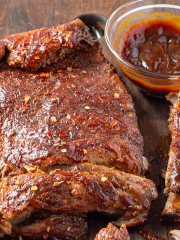 pork ribs in a wooden chopping board with brown dip sauce on the side