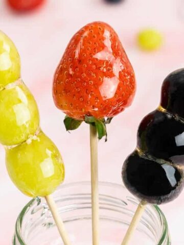 skewered strawberry, green grapes and blueberry coated in a crunchy, hardened sugar glaze.