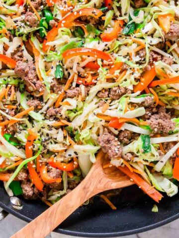 ground beef with cabbage, red bell pepper, shredded carrots, chopped green onions and sesame seeds for garnish