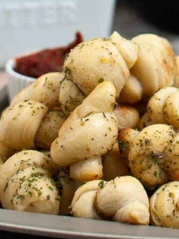 Garlic Knots bread on a tray with red dipping sauce on the side