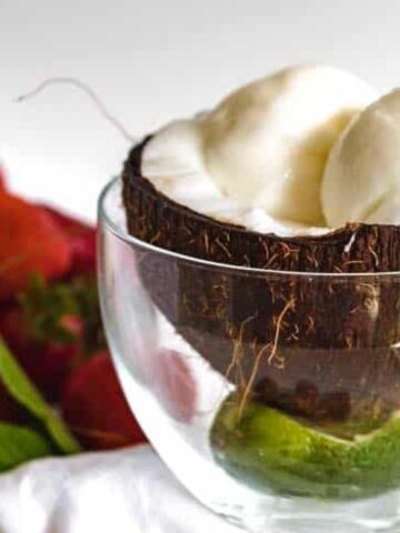 coconut ice cream on a cup of glass garnished with mint leaves and strawberry fruits on the background